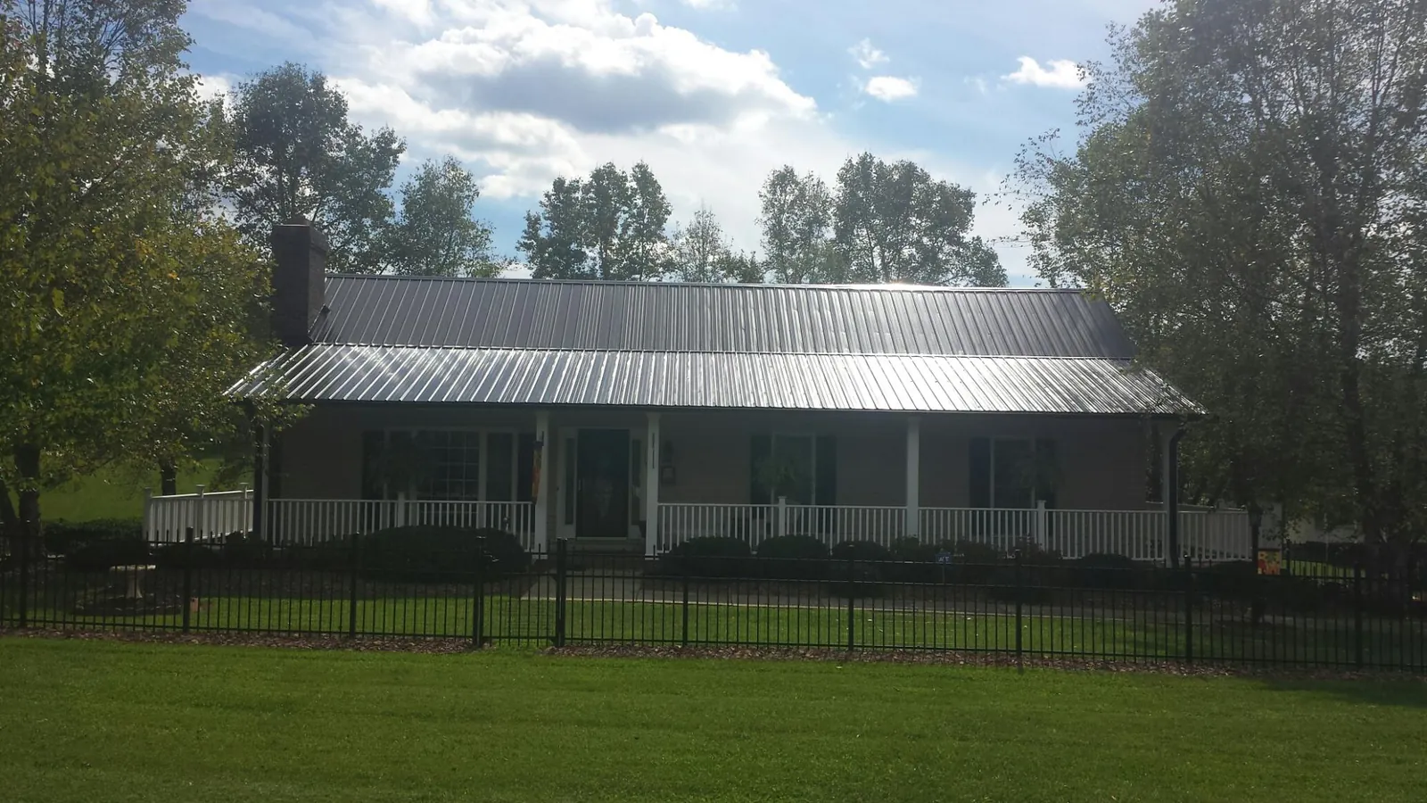 Gray metal roof on a brick ranch with a full width front porch — Gutter Guard Installation work by our crew in Altoona