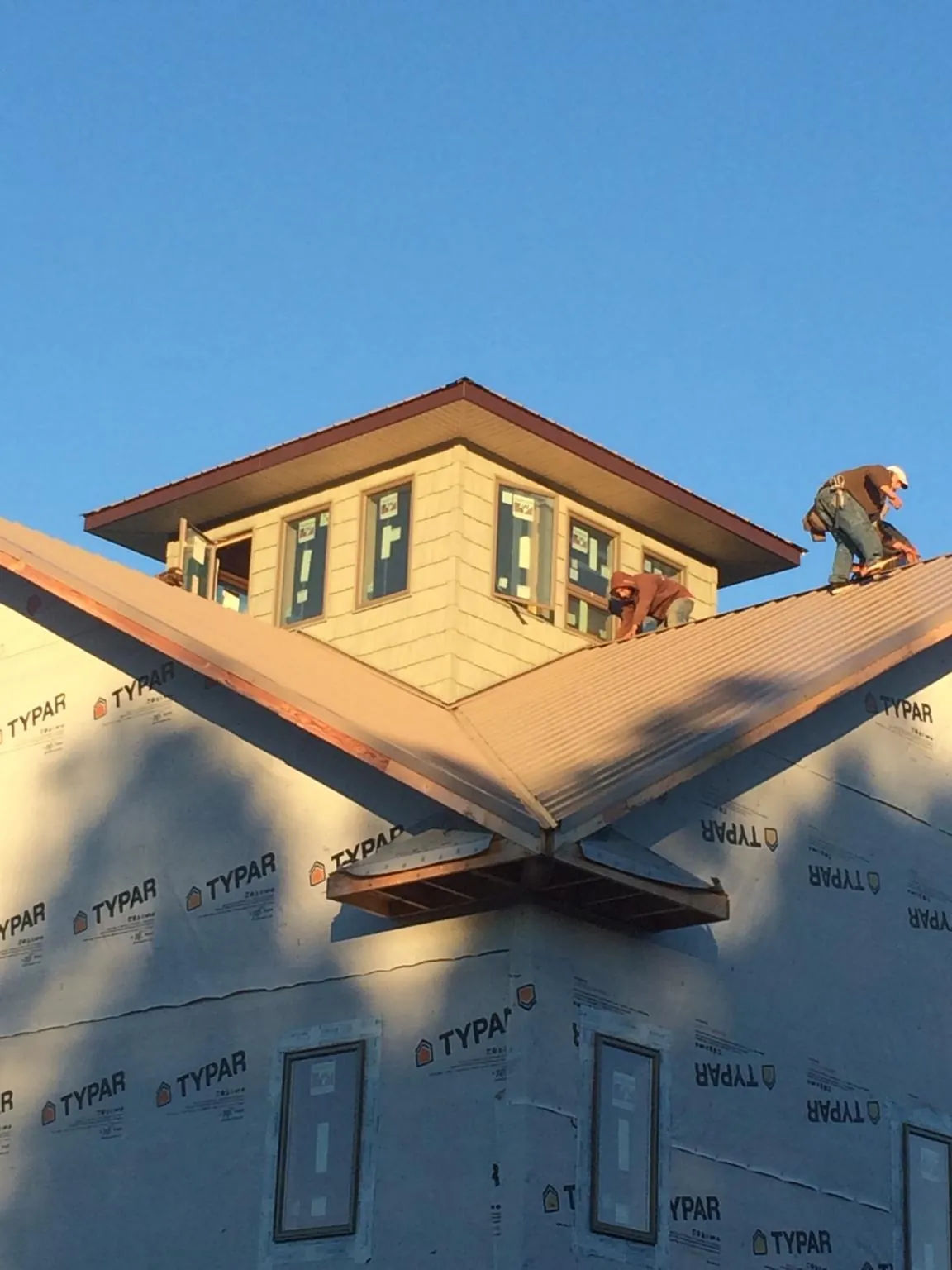 Roofers working around a rooftop cupola on a new metal roof at sunset — Roof Waterproofing in Altoona by Roofing Brothers